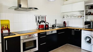 A modern kitchen with black cabinets, a red kettle, and a washing machine.