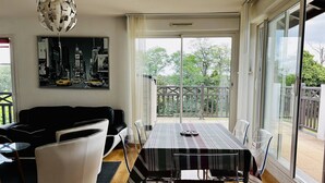 A modern living room with a dining area, large windows, and a balcony.