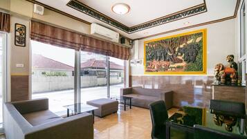 A lobby with a large window, a sofa, a chair, and a table.