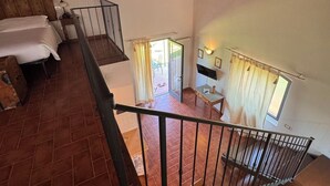 A spacious room with a high ceiling, a wooden staircase, and a view of an outdoor area. - Olivaia-beautiful loft apartament with view (Reggello)
