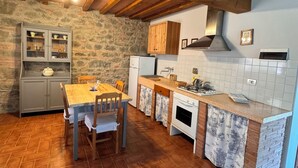 A rustic kitchen with a wooden table, stone walls, and a tiled backsplash. - Olivaia-beautiful loft apartament with view (Reggello)
