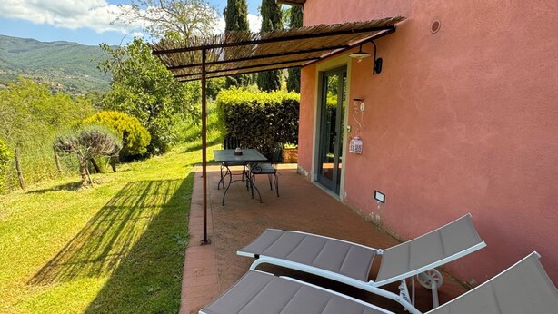 A patio with two sun loungers, a table, and chairs, a pergola, and a view of the countryside. - Olivaia-beautiful loft apartament with view (Reggello)