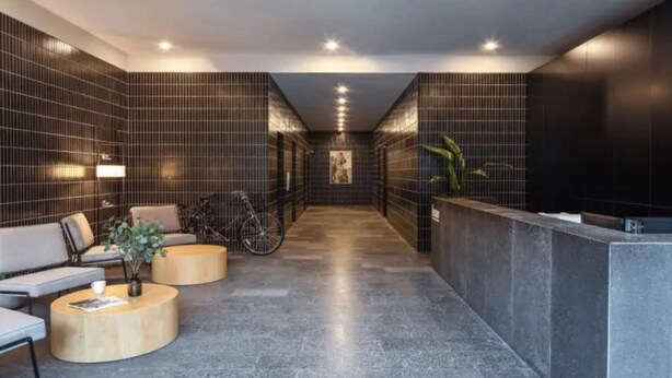 A modern reception area with a reception desk, seating area with sofas and round tables, a bicycle, and a plant. - BaseLIVING Wending Serviced Apartment (Shanghai)
