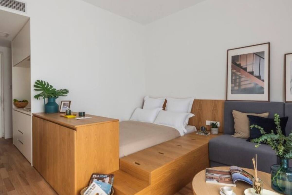 A modern bedroom with a built-in bed, a wooden desk, a sofa, and a coffee table.