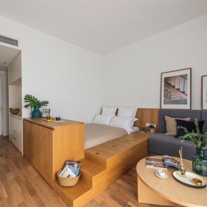 A modern bedroom with a built-in bed, a wooden desk, a sofa, and a coffee table. - BaseLIVING Wending Serviced Apartment (Shanghai)