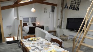 A compact room with a dining table set for two, a bed with a headboard, a TV, and a ladder. - Independent studio on the 1st floor less than 1 kilometer from the Château de Lavaux (Rochefort)