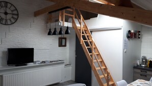 A kitchen with a wooden ladder, a clock, and a dining area with a table and chairs. - Independent studio on the 1st floor less than 1 kilometer from the Château de Lavaux (Rochefort)