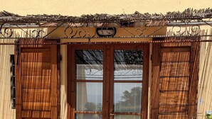 Une terrasse avec une table et des chaises, une porte en bois dotée de panneaux de verre et une clôture en bambou.