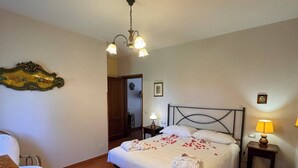 Une chambre à coucher comprenant un lit, deux tables de chevet avec des lampes, une chaise, un bureau et un élément décoratif mural.