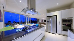 Una cucina moderna con isola centrale, elettrodomestici in acciaio inossidabile e un'ampia finestra con vista sulla città.