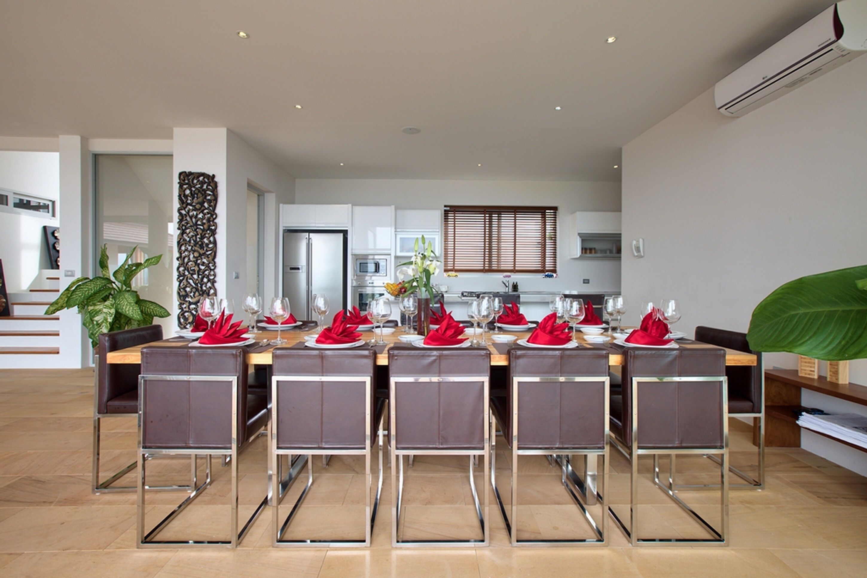 Un espace de restauration moderne avec une longue table dressée pour six personnes, entourée de chaises à structure métallique.