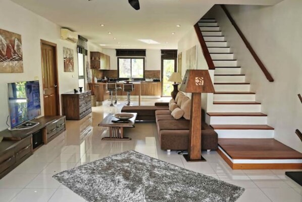 Un salon moderne avec un canapé, une table basse et un escalier.