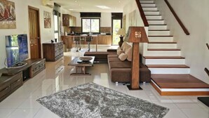 A modern living room with a staircase, a kitchen, and a dining area. - 4 Bedroom Twin Villas Cheong Mon (Koh Samui)