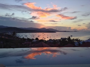 A coastal view with boats at sunset, a clear sky, and a tiled swimming pool in the foreground. - 3 Bedroom Sunset Sea View Villa SDV097-By Samui Dream Villas (Koh Samui)