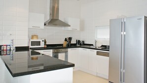 A modern kitchen with white cabinets, a stainless steel range hood, a microwave, a coffee maker, and a refrigerator. - 3 Bedroom Sunset Sea View Villa SDV097-By Samui Dream Villas (Koh Samui)