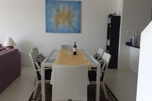 A dining area with a table set for two, surrounded by chairs, a wine bottle, and a decorative wall piece. - 6 Bedroom Sunset Sea Views Twin Apartments SDV120/097-By Samui Dream Villas (Koh Samui)