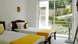 A hotel room with two beds, a large window with a view of a garden, and a standing fan. - 6 Bedroom Sunset Sea Views Twin Apartments SDV120/097-By Samui Dream Villas (Koh Samui)
