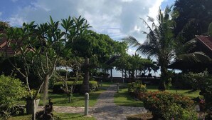 Un sendero en un jardín que lleva a un edificio con vista al mar.