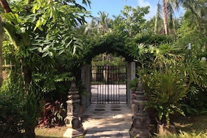 Stroll through the serene garden, surrounded by lush greenery and tropical plants, to a secure gated entrance.