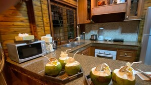 Una cocina con encimeras de granito, microondas, fregadero y tostadora. Hay tres cocos sobre la encimera.
