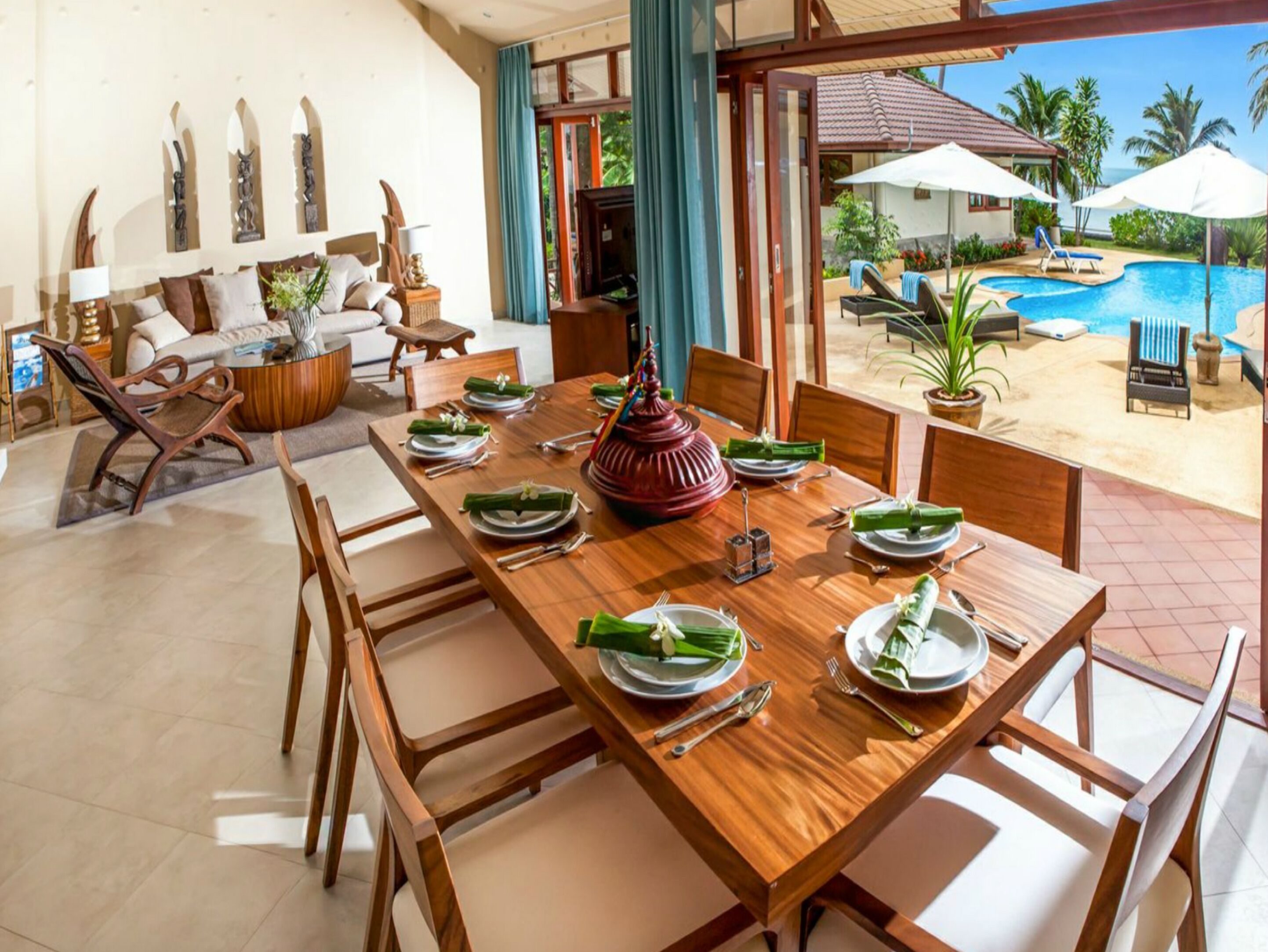A dining area with a wooden table set for six, surrounded by wooden chairs.