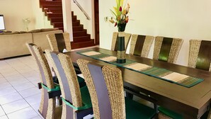 A dining area with a long table, woven chairs, and a vase of flowers. - 4 Bedroom Villa on Beachfront Resort TG39 (Koh Samui)