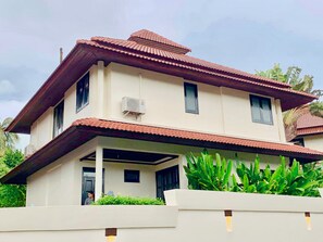 A two-story house with a tiled roof and a covered porch.