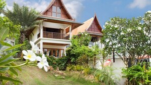 A two-story house with a sloped roof, surrounded by lush greenery and a clear sky. - 6 Bedroom Sea View Villas Kai Muk Mussourie (Koh Samui)