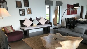 A modern living room with a sofa, a coffee table, and a red ottoman. - 12 Bedroom Luxury Twin Sea View Villas Angthong (Koh Samui)