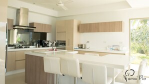 A modern kitchen with a central island, white bar stools, and wooden cabinetry. - 12 Bedroom Luxury Twin Sea View Villas Angthong (Koh Samui)