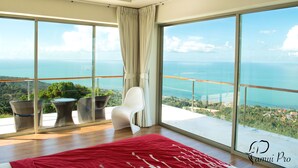 A spacious balcony with a red rug, wicker chairs, and a white chair overlooking a coastal view. - 12 Bedroom Luxury Twin Sea View Villas Angthong (Koh Samui)