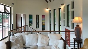 A modern living room with a sofa, a lamp, and a staircase leading to another level. - 3 Bedroom Sea View Villa Santi SDV228-By Samui Dream Villas (Koh Samui)