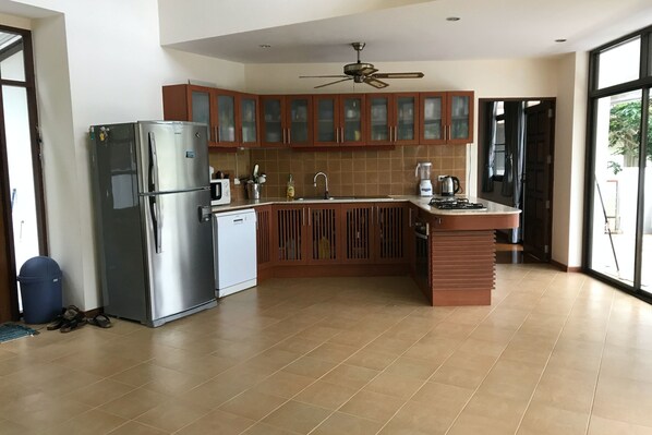 A modern kitchen with a stainless steel refrigerator, wooden cabinets, a built-in sink, and a gas stove.