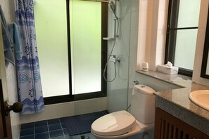 Een badkamer met douche, toilet en wastafel.