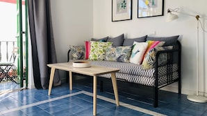 Uma sala de estar aconchegante com um sofá estampado, uma mesa pequena e um abajur.