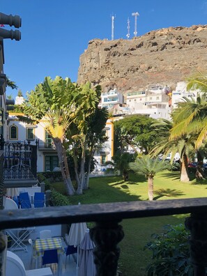 Vista di una zona costiera con edifici, palme e una scogliera rocciosa.