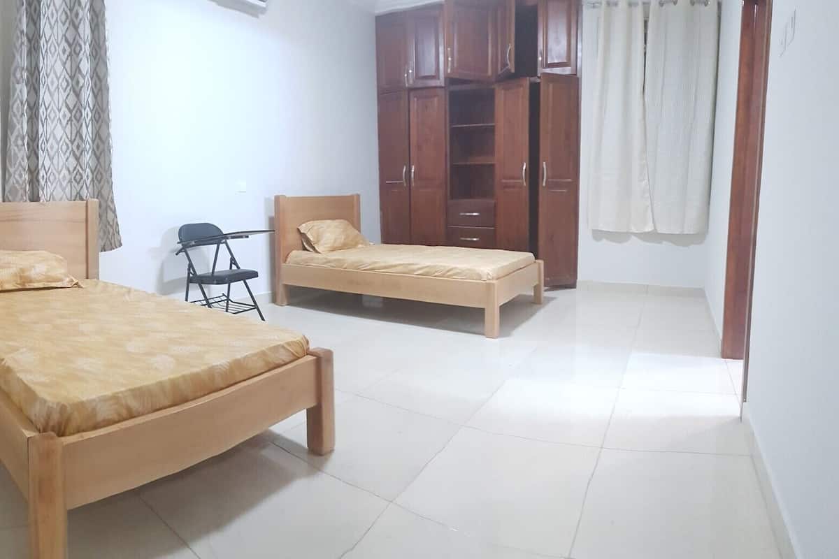 A room with two wooden beds, a chair, a wardrobe, and a small table.