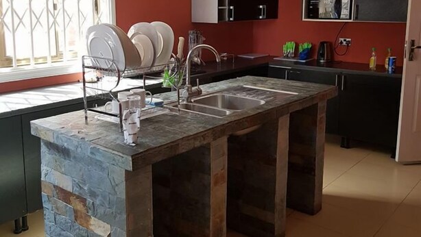 Una cocina con una isla central, una ventana con rejas y un ventilador de techo.