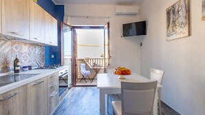 Een compacte keuken met een eethoek, een aan de muur bevestigde televisie en een balkon met uitzicht.