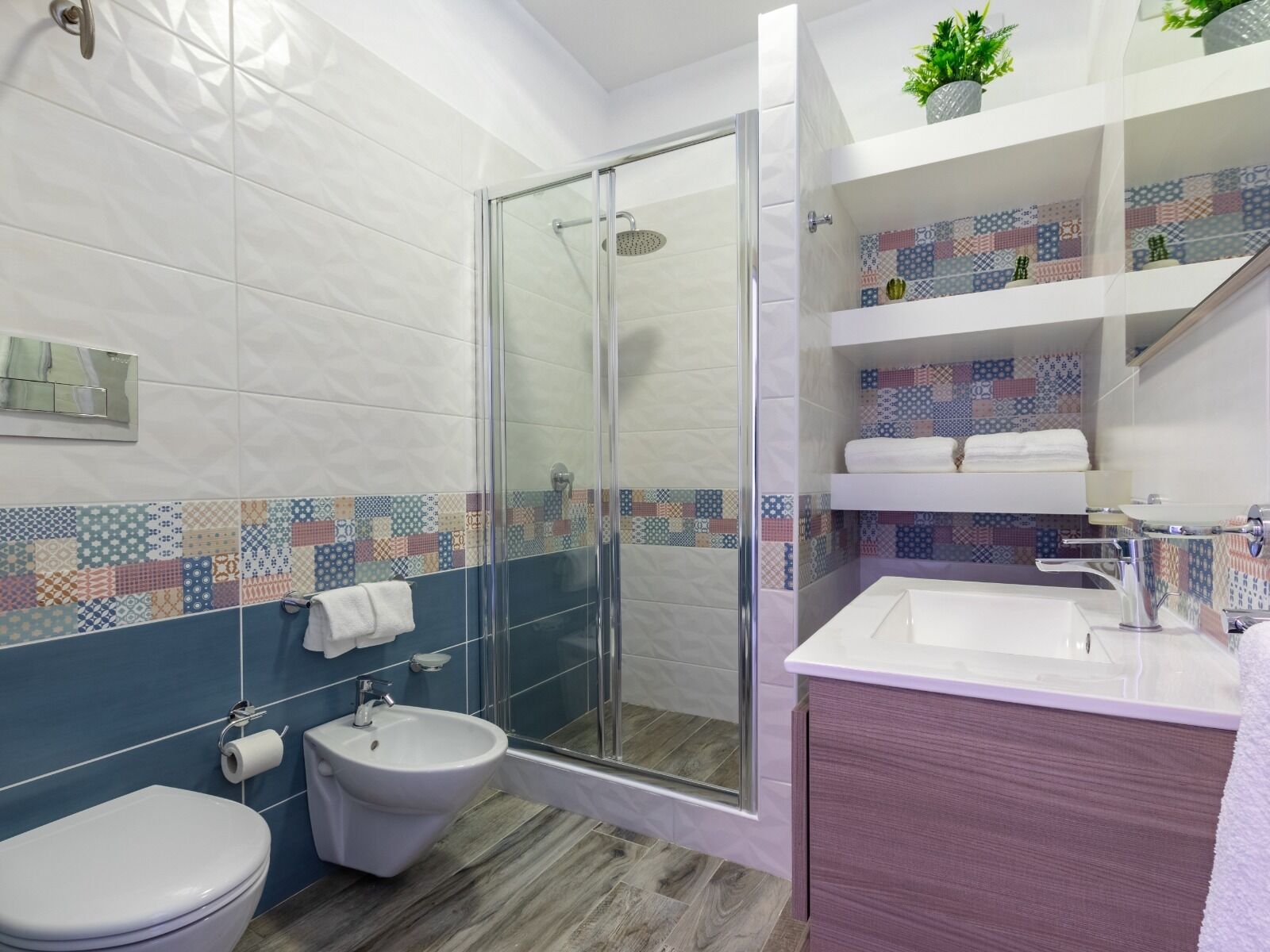 A modern bathroom with a glass shower enclosure, a bidet, a toilet, and a vanity with a sink and mirror.