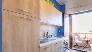 Een moderne keuken met houten kastjes, een gasfornuis en uitzicht op het balkon.
