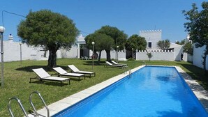 A swimming pool with lounge chairs and a white building in the background. - CASA SALON - Hacienda Finca Mangueta (Vejer de la Frontera)