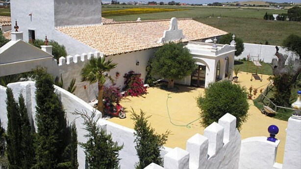 A white building with a tiled roof, surrounded by greenery and a clear sky. - CASA SALON - Hacienda Finca Mangueta (Vejer de la Frontera)