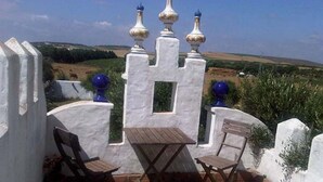 A patio with a table and two chairs, white walls, and decorative blue spheres. - CASA SALON - Hacienda Finca Mangueta (Vejer de la Frontera)