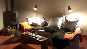 A cozy living room with a sofa, two lamps, a table with candles, a fireplace, and a window with curtains. - 90m² holiday house in Dhronecken (Dhronecken)