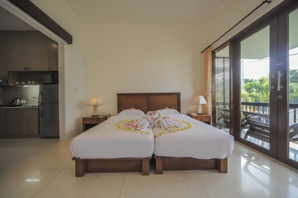 A hotel room with a double bed, a small kitchenette, and a balcony with outdoor furniture. - Sayang Sanur Resort (Denpasar)