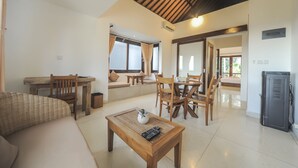 A spacious living area with a sofa, wooden dining table, chairs, and a coffee table. - Sayang Sanur Resort (Denpasar)