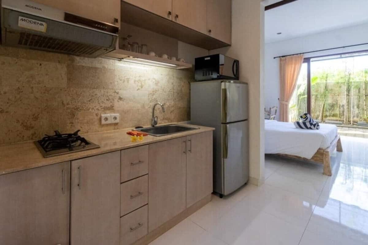 A modern kitchen with a built-in stove, sink, and refrigerator. There is a bed with a view of the outdoors.