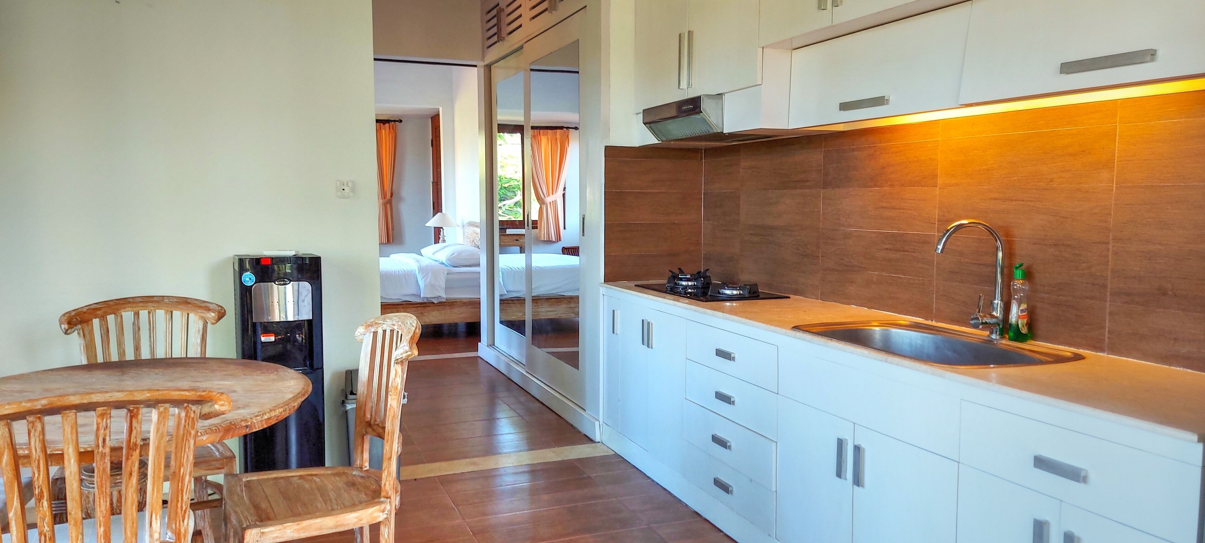 A compact kitchen with a sink, stove, and cabinets. There is a dining area with a table and chairs.
