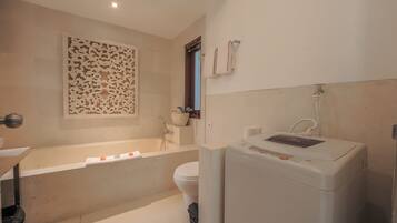 Ein Badezimmer mit Badewanne, Toilette und Waschmaschine.